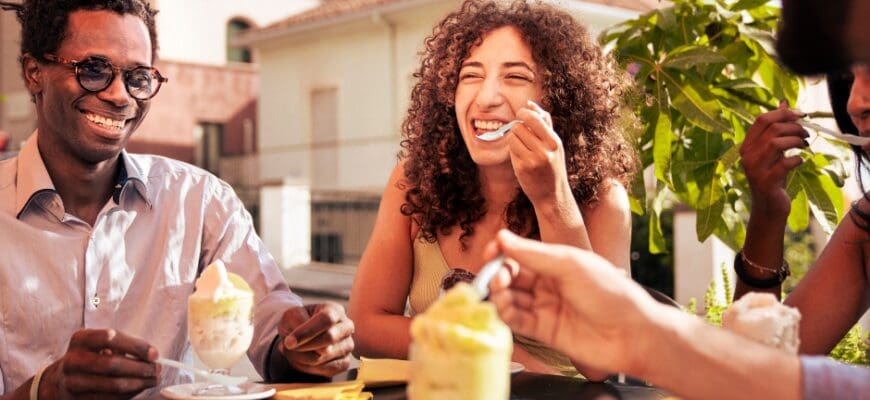 Three people eating ice cream at an outdoor restaurant table